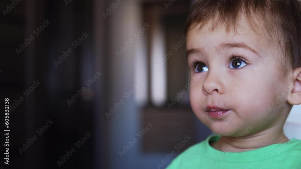 Beautiful dark-haired toddler is fed from spoon. Little child’s nutrition. Close up. Blurred backdrop. Beautiful dark-haired toddler is fed from spoon. Little child’s nutrition. Close up. Blurred backdrop.