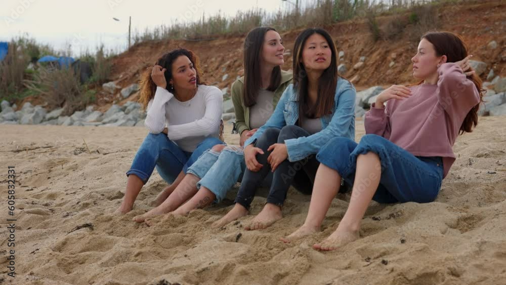 Four young girls looking around while sitting on beach Four young girls looking around while sitting on beach