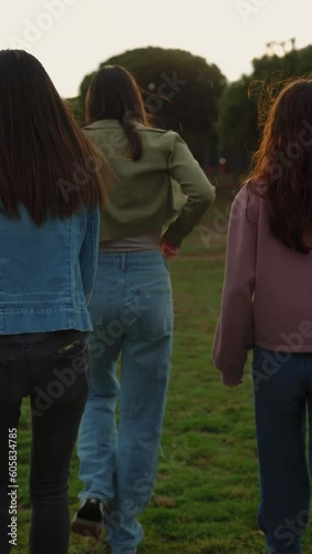 Rare view of four girls walking together on field during rainy day.