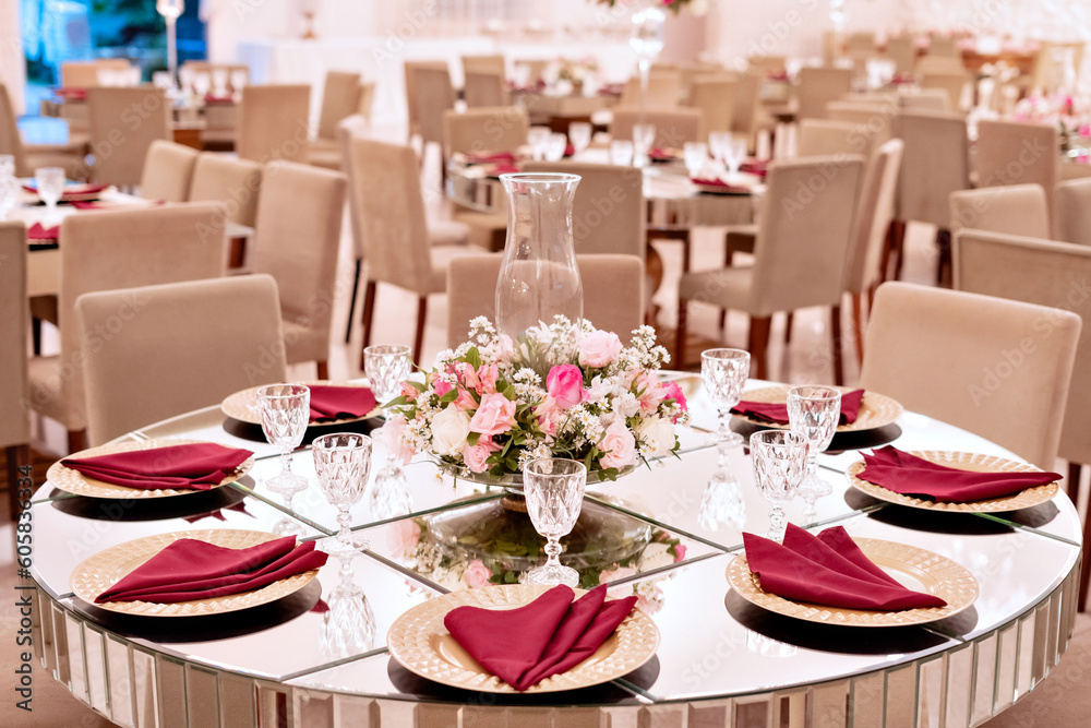 a table with a glass top, sousplat and pink napkins with an arrangement in the center