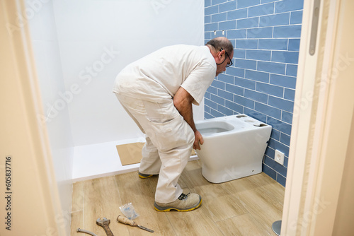 Billede på lærred Senior plumber installer installing toilet in a bathroom.