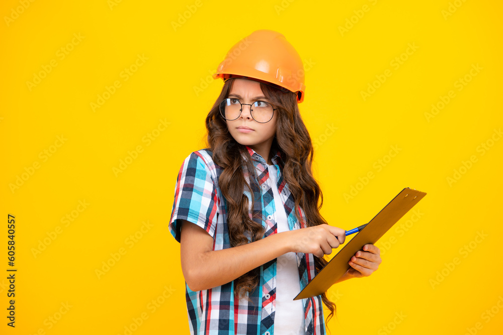 Thinking pensive clever teenager girl. Teenager child painter in helmet with clipboard. Child in hard hat. Kid engineer on construction site. Renovation and repair. - obrazy, fototapety, plakaty 