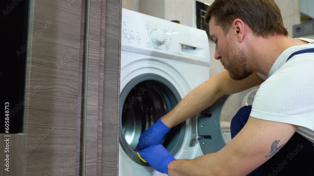 A man in blue gloves cleans a dirty, moldy rubber seal on a washing