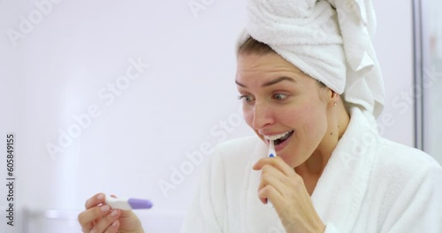 Pregnancy, test and happy woman brushing teeth in bathroom with surprise results. Excited female person, morning routine and stick of pregnant news of fertility healthcare, hormones and ivf at home photo
