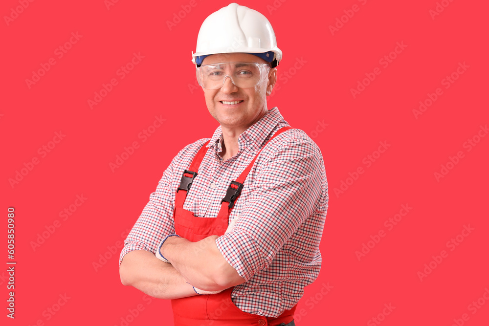 Mature carpenter in hardhat on red background Mature carpenter in hardhat on red background