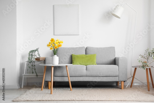 Fotografiet Interior of living room with grey sofa and blossoming narcissus flowers on coffe