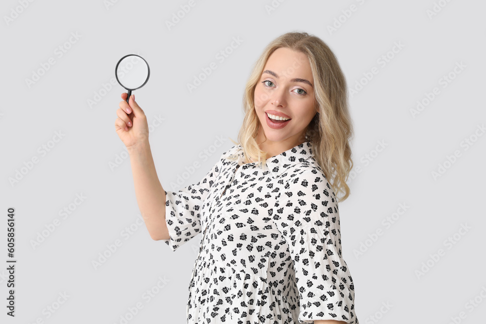 Young woman with magnifier on light background Young woman with magnifier on light background