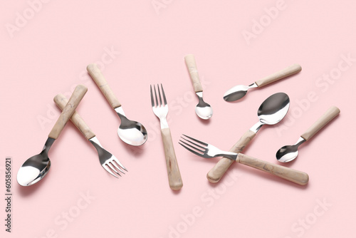 Stylish forks and spoons on pink background