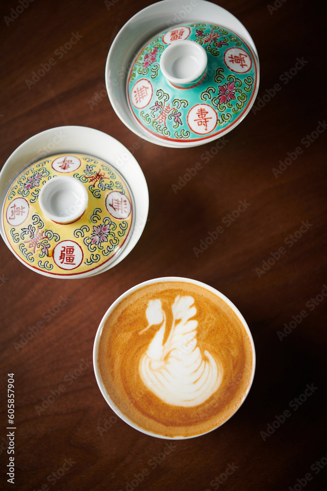 Cappuccino with latte art in a unique and antique chinese cup on a wooden table. Cappuccino with latte art in a unique and antique chinese cup on a wooden table.