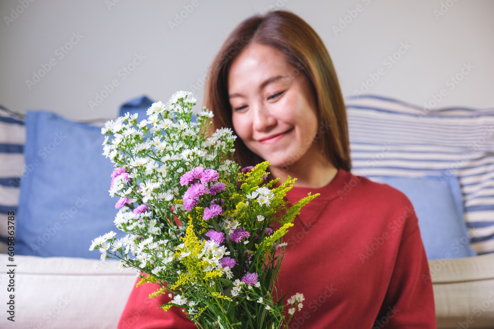 Portrait image of a beautiful young asian woman holding and looking at a flower bouquet at home Portrait image of a beautiful young asian woman holding and looking at a flower bouquet at home