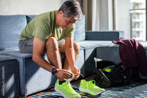 Middle aged man tying his shoelaces and getting ready to go workout