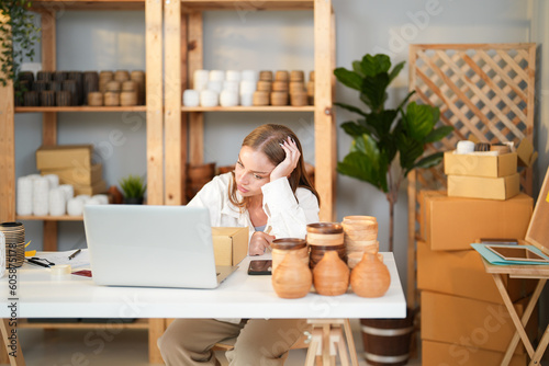 Caucasian entrepreneur girl tired and stress about business problem and lose the money of the first product lot cannot sell when she check online order in the computer at home office
