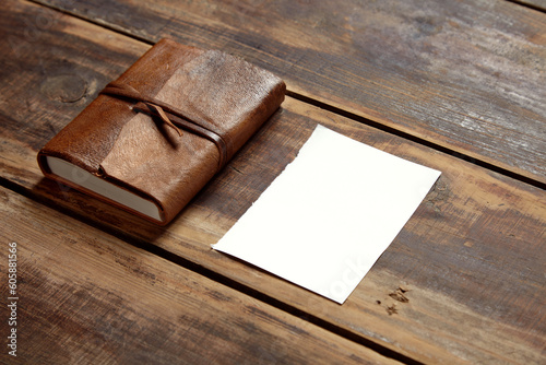 notbook and a sheet of paper on a wooden table from aside