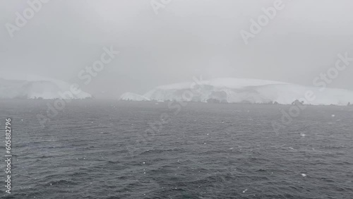 Panning view across the bow onboard expedition ship at Antarctica's Melchior Islands during snow storm. Poor visibility with high winds and moderate sea state. photo