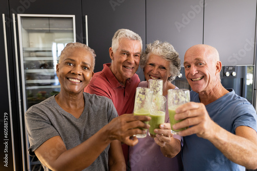 Portrait of happy diverse senior friends making a toast with healthy smoothies in kitchen