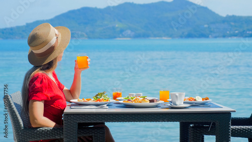 Woman enjoy beautiful and healthy breakfast at luxury hotel by the sea in tropics. Vacation breakfast table with stunning view of ocean and. Relaxing travel holiday on Phuket Island, Thailand, Asia.