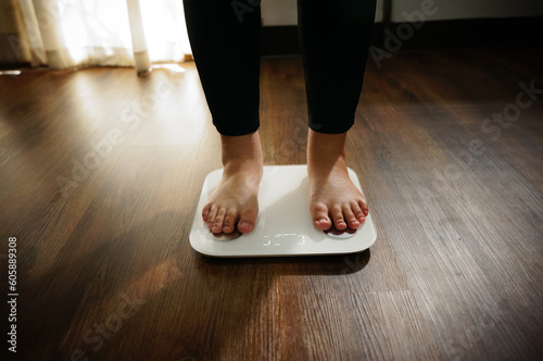 Fat diet and scale feet standing on electronic scales for weight control.