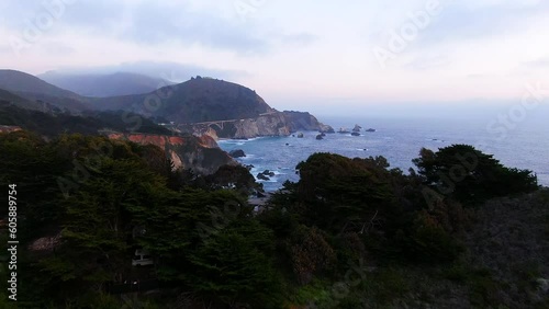 Aerial Cinematic drone early spring field coastline Big Sur Rock Creek Bixby Bridge coastal Highway 1 vista point California sunrise sunset morning rugged deep blue ocean forward pan up motion photo