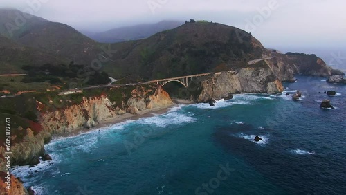Aerial Cinematic drone early spring coastline Big Sur Rock Creek Bixby Bridge coastal Highway 1 vista point California sunrise sunset morning stunning rugged deep blue ocean pan up forward motion photo