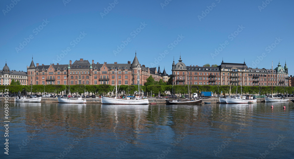 The pier at the street Strandvägen with od fishing boats and apartment houses, a sunny summer day in Stockholm