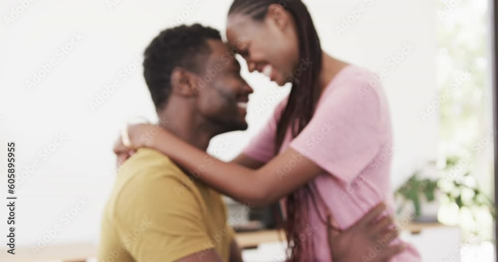 Happy african american couple smiling and embracing in living room, in slow motion Happy african american couple smiling and embracing in living room, in slow motion
