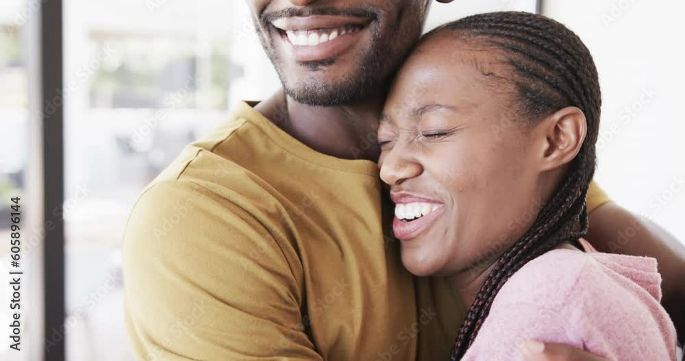 Happy african american couple smiling and embracing in living room, in slow motion Happy african american couple smiling and embracing in living room, in slow motion