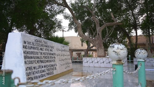 Marble stone with inscription in English and Arabic with Tree of Adam or of Knowledge in background, El Qurna in Iraq photo