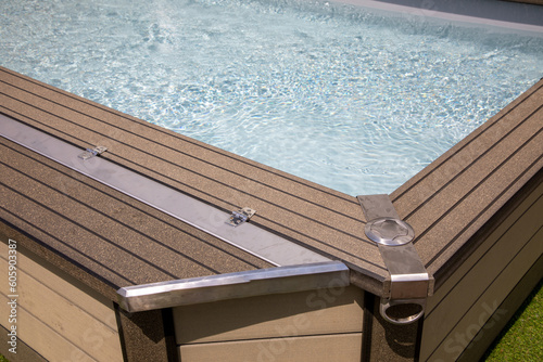 corner of a modern brown exterior private spa and full of translucent swimming pool water