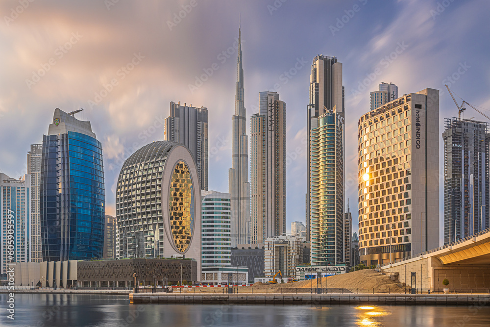 Sunset in Dubai. City center with commercial buildings and skyscrapers around Burj Khalifa. Skyline in the evening at sunset with a cloudy sky. reflecting sunlight on the glass facades of the building