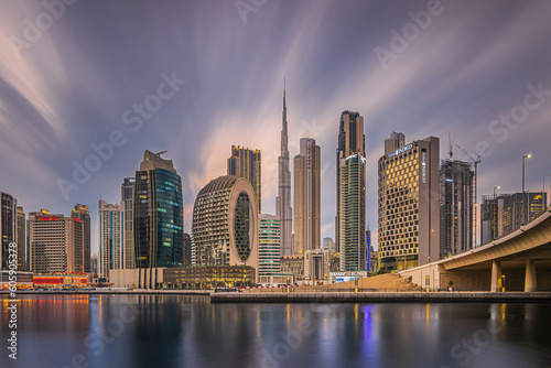 Dubai in the evening after sunset. United arab emirates city skyline. High-rise buildings with lighting. City center view. Reflection of the city lights on the smooth water surface