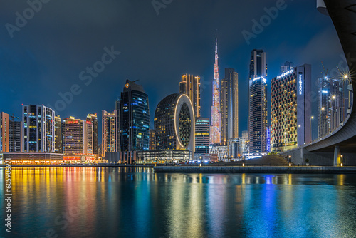 Modern buildings in the city center of Dubai in the evening. Illuminated skyscrapers in the financial center at the blue hour. View of skyline in united arab emirates at night and reflection
