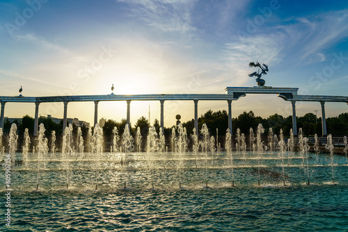 Memorial and rows of fountains illuminated by sunlight at sunset or sunrise in the Independence Square at summertime, Tashkent. photo