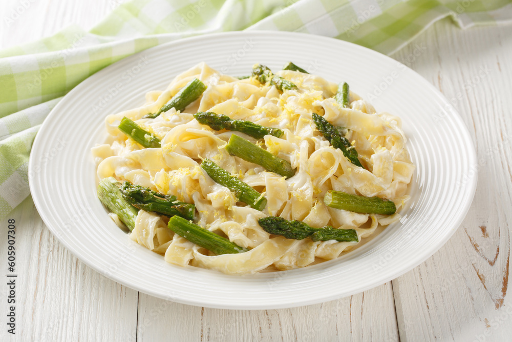 Asparagus Pasta with Lemon zest and Parmesan closeup on the plate on the wooden table. Horizontal Asparagus Pasta with Lemon zest and Parmesan closeup on the plate on the wooden table. Horizontal