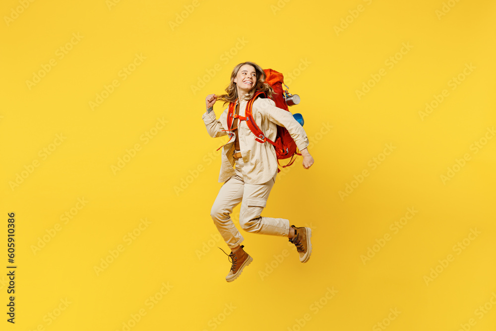 Full body young woman carry bag with stuff mat jump high look aside on area isolated on plain yellow background. Tourist leads active lifestyle walk on spare time Hiking trek rest travel trip concept