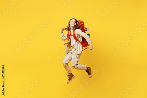 Full body young woman carry bag with stuff mat jump high look aside on area isolated on plain yellow background. Tourist leads active lifestyle walk on spare time Hiking trek rest travel trip concept