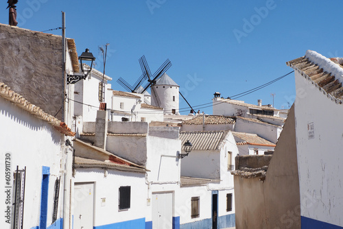 beautiful street in the town of campo de criptana with the windmills in the background photo