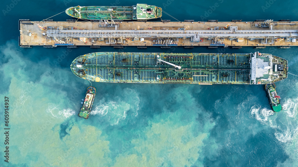 Aerial view oil tanker ship at terminal industrial port tugboat drag ...