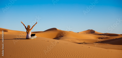 Girl freelancer working on the dune sand in the desert- business, success, travel concept