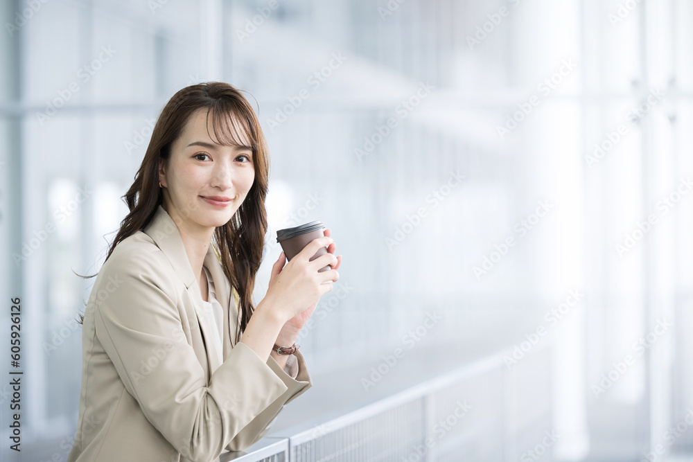 オフィスビルで見上げるスーツ姿の美しい女性 コーヒーを飲んで休憩する カメラ目線 オフィスビルで見上げるスーツ姿の美しい女性 コーヒーを飲んで休憩する カメラ目線