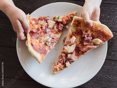 anonymous child's hand picks up a slice of pizza