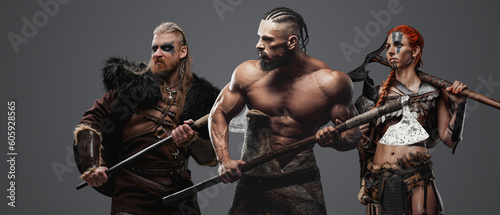 Studio shot of three scandinavian barbarians from past against grey background.