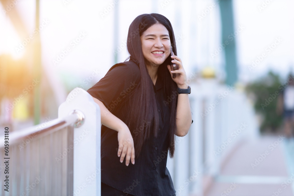 Portrait asian woman tourist in black shirt dress with a smartphone on Route walking jogging or ride bicycle and exercise on the bridge.