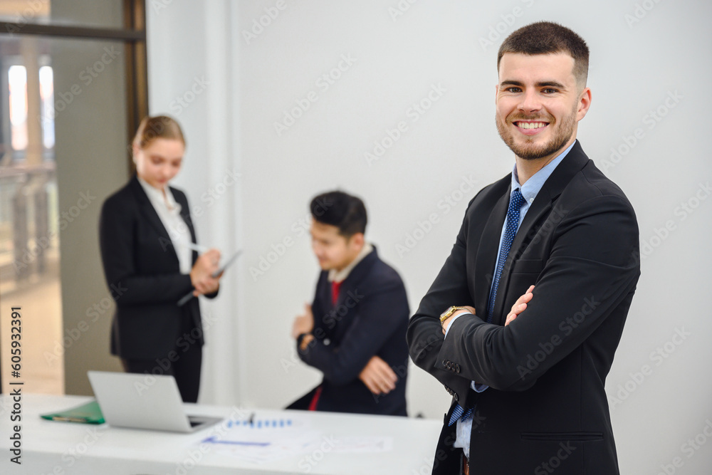Portrait of a happy smiling businessman looking at the camera in a conference room Handsome working manager smiling confidently standing in office at team meeting Portrait of a happy smiling businessman looking at the camera in a conference room Handsome working manager smiling confidently standing in office at team meeting