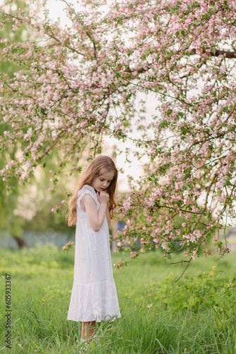 a girl in a green summer park looking at a flower