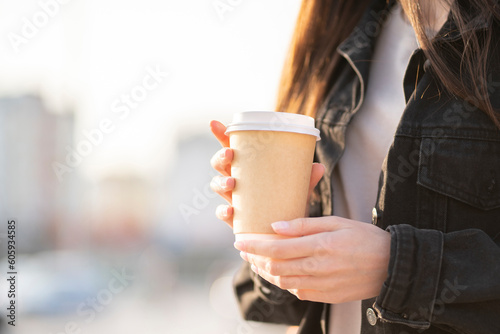 Fényképezés woman is holding a takeaway cup of hot drink outdoors on a summer day in the cit