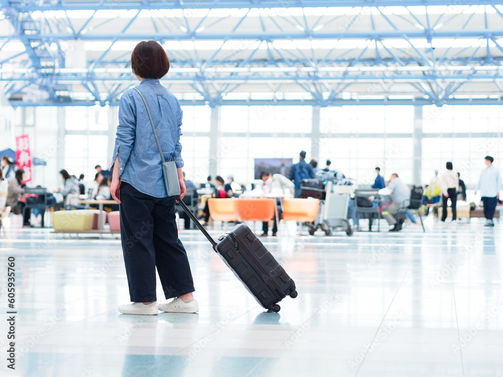 空港でスーツケースを持って旅行に出発する女性のイメージ
