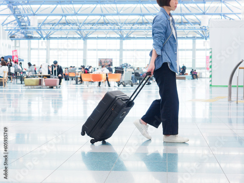 空港のロビーでスーツケースを持って歩く女性