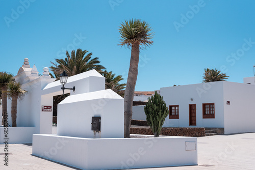 Typical Canary Islands street with white houses, green wooden doors and windows and colorful flowers in Teguise village, Canary Islands, Spain.