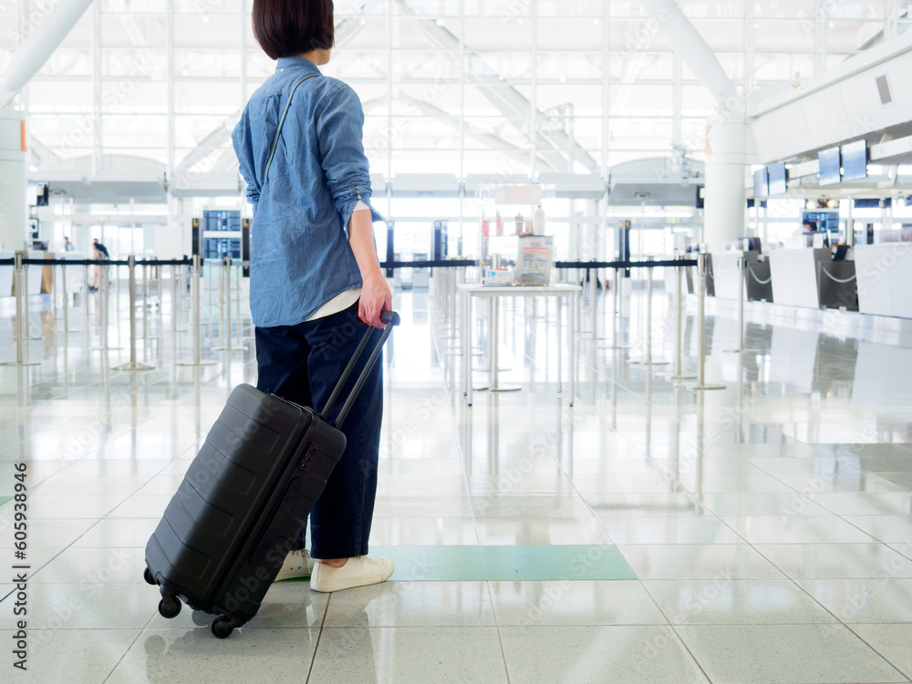 空港でスーツケースを持って旅行に出発する女性のイメージ