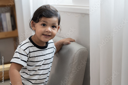 Happy smiling cute little toddler boy playing in living room at home